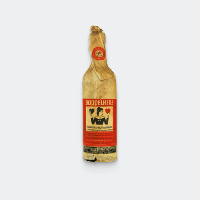 A vintage bottle of Doppelherz, featuring a distinctive red label with black illustrations and text. The bottle is wrapped in brown paper, giving it an aged appearance. The label includes a logo and information about the product.
