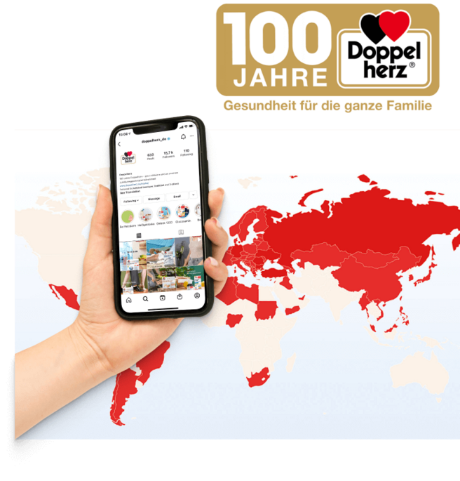 An informative graphic celebrates 100 years of Doppelherz, featuring a hand holding a smartphone displaying an Instagram page. A world map, primarily in red, highlights specific regions, emphasizing the brand's global presence and commitment to health for families.